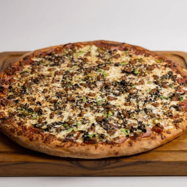 A Fiesta Pizza with sausage, mushrooms, and green peppers on a wooden board.