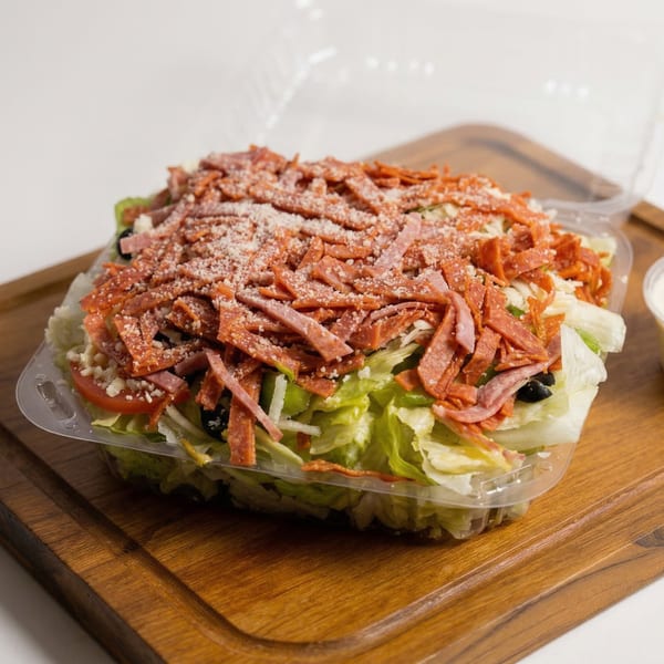 A large Fiesta Pizza salad with pepperoni, salami, cheese, and olives in a clear plastic container.