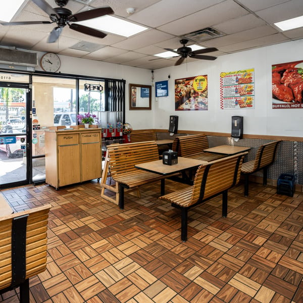 Interior of Fiesta Pizza with wooden benches, tables, and pizza deal posters on the walls.